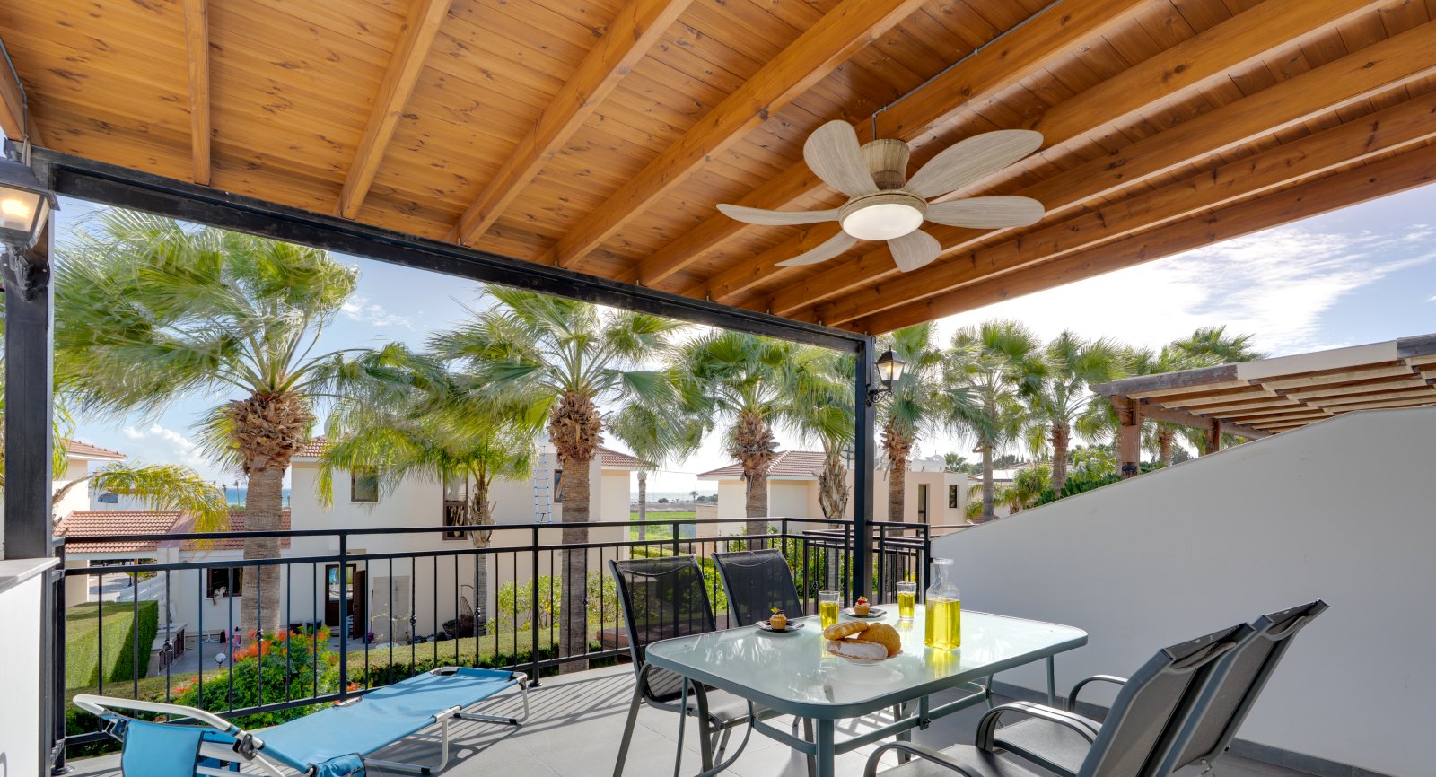 Covered veranda with ceiling fan, palm garden and sea view at the Lux Sandy Beach Suite